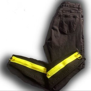 Black jeans with neon yellow zipper at the bottom .